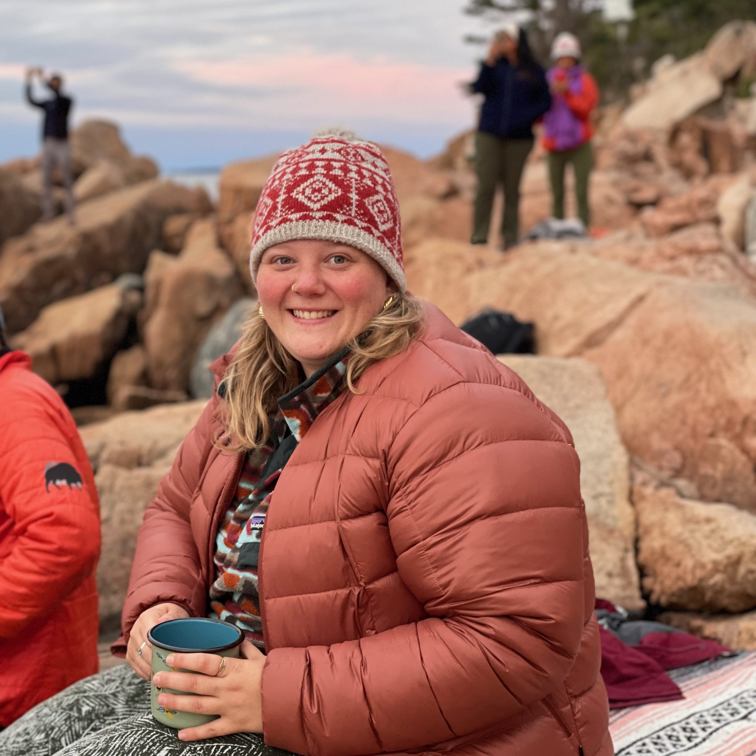 Joelle Kilchenmann sitting with a cup on a mountain