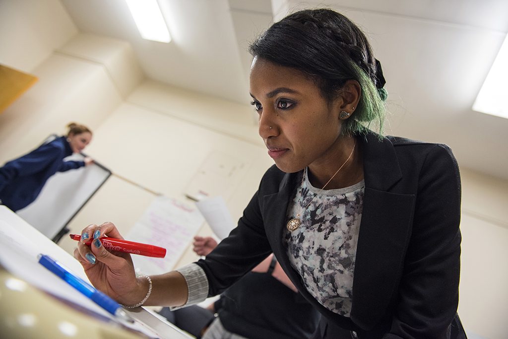 A photo of a student at a table, pen in hand.