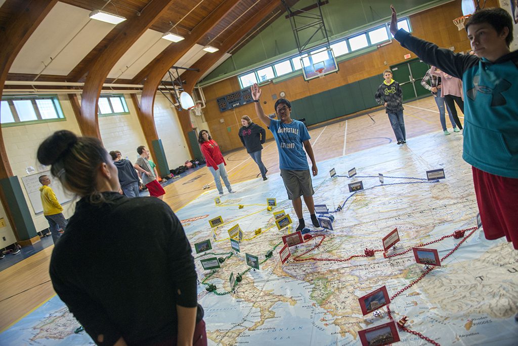 A photo of Leonard Middle School students learning about geography with a giant National Geographic map.