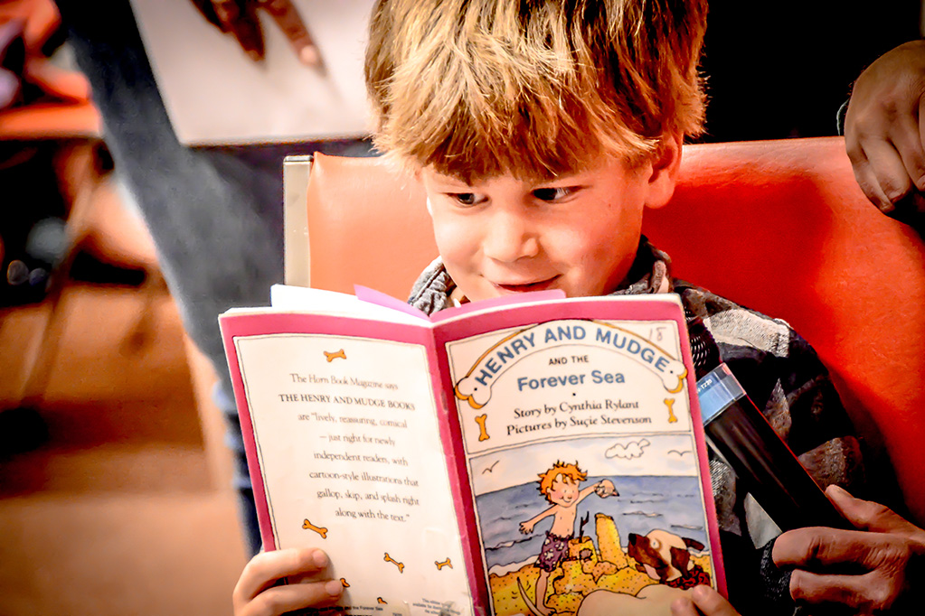 A photo of a smiling child reading a book.