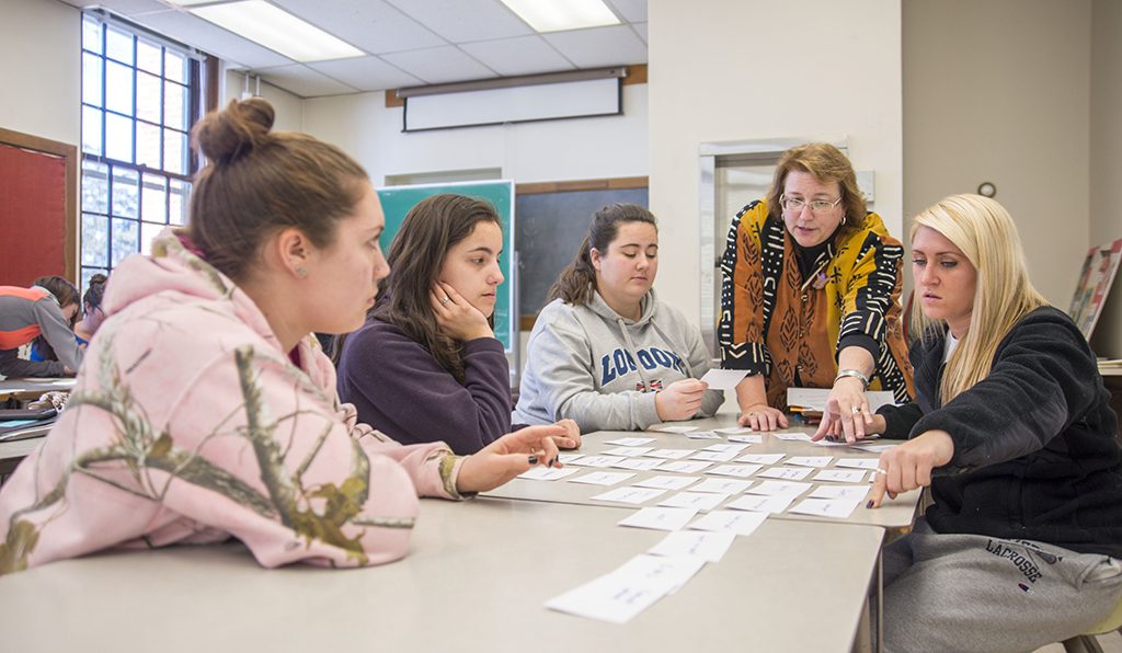 A group of people around a table looking at a layout of note cards, a brainstorming session.