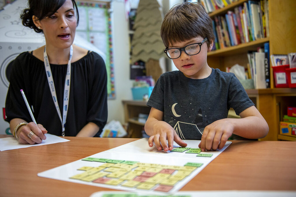 A photo of a teacher working with an elementary student learning about letters.