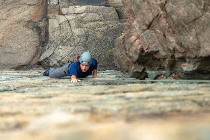 A rock climber ascends a rock wall in Maine.
