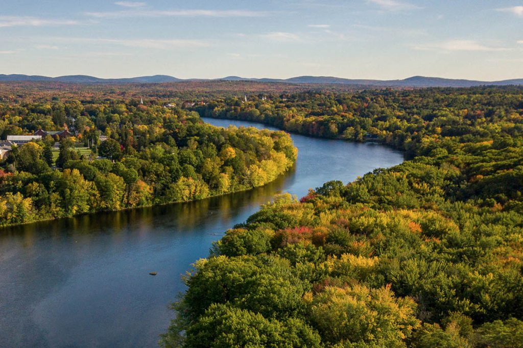 An aerial photo of the Stillwater River, with the University of Maine campus in the background.