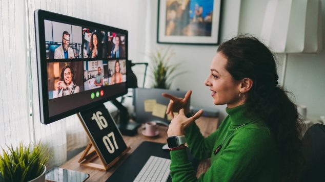 A photo of a woman talking to a group of people on a video call.