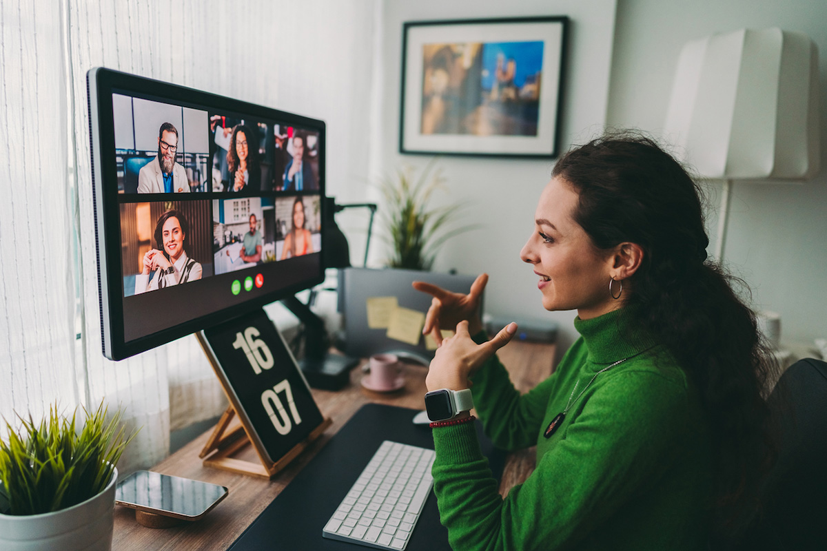 A photo of a woman talking to a group of people on a video call.