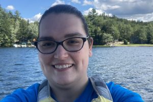 Sara Pomeroy selfie in an outdoor setting with a lake in the background.