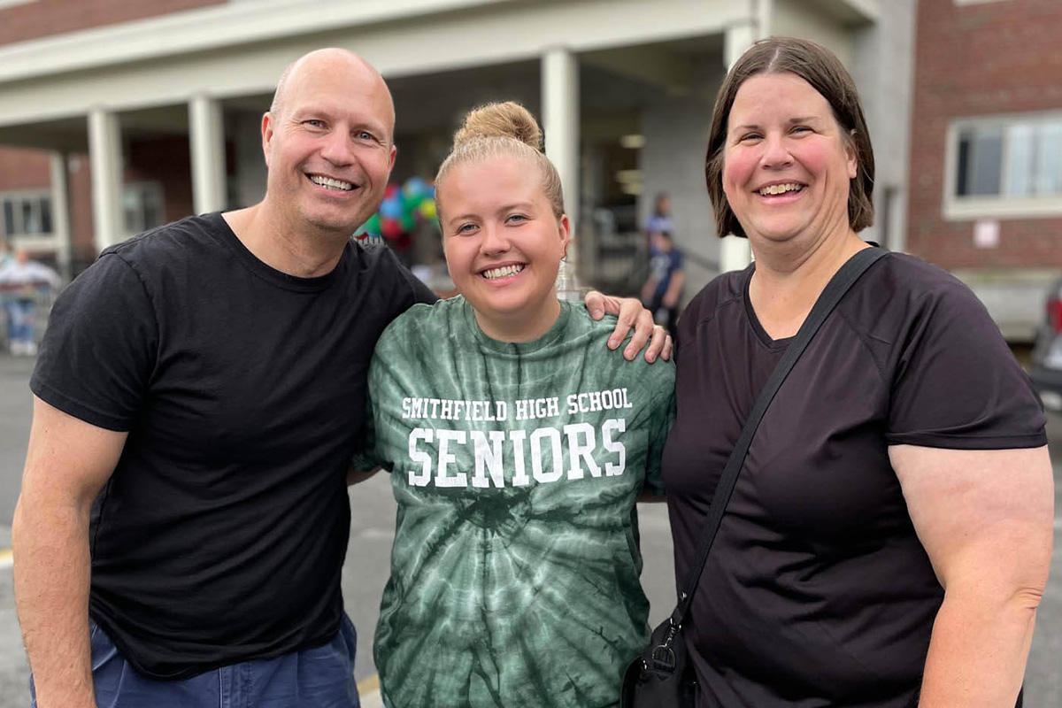 A photo of Natalie Tomah and her parents Tony and Lori Tomah in front of Cumberland Hall on the University of Maine campus.