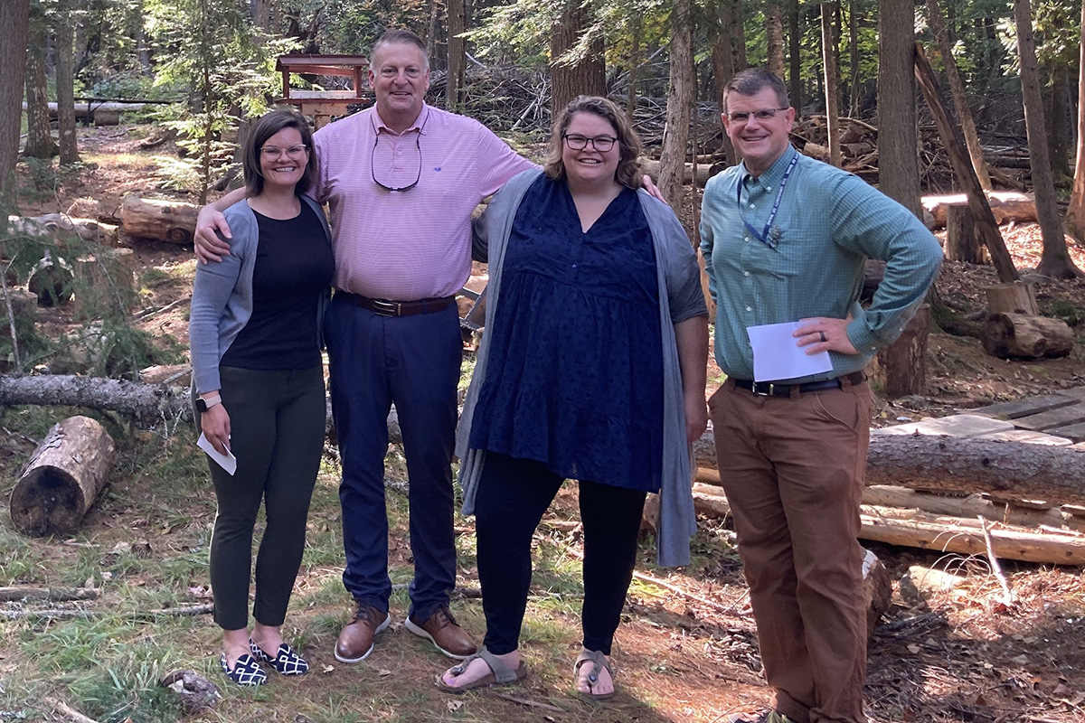 Taylor McCabe-Juhnke, Allen Pratt, Catharine Biddle and Jon Doty pose for a photo in the woods in Old Town, Maine.