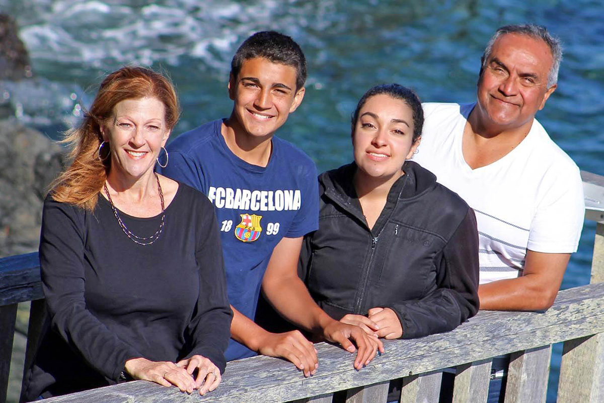 A photo of a family of four standing in front of water.