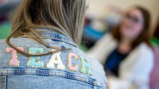 A photo of a teacher's denim jacket with the word "TEACH" across the back.