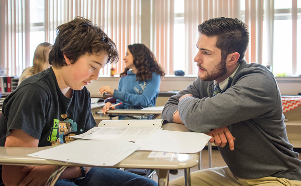 A photo of a UMaine student working with a student
