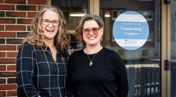 A photo of Angela Fileccia and Sarah Howorth in front of the University of Maine Counseling Center.