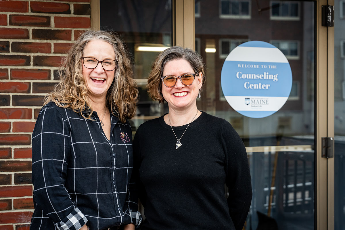 A photo of Angela Fileccia and Sarah Howorth in front of the University of Maine Counseling Center.