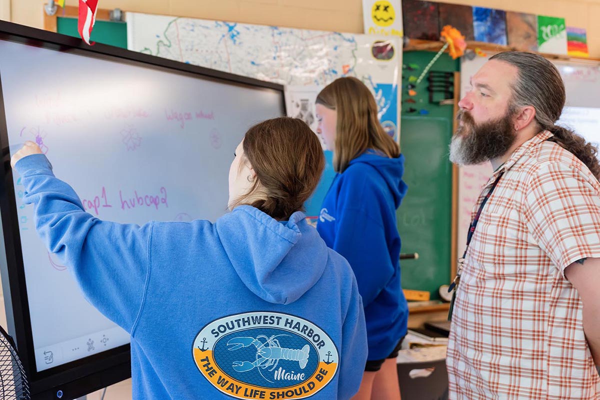 A photo of three people in a classroom.
