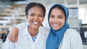 Two women stand together in lab coatsd