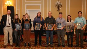 A group of people holding awards in a carpeted ballroom