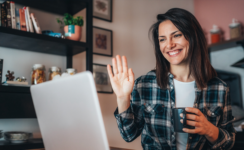 A photo of a woman waving at a laptop