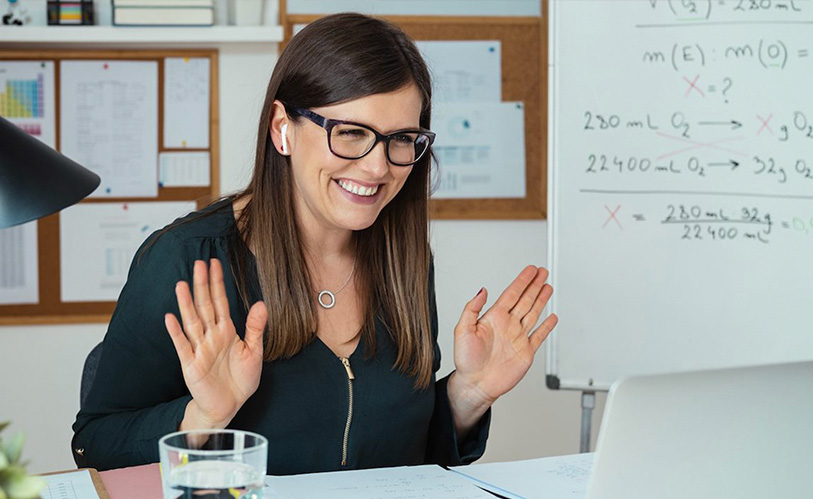 A stock image of a woman waving at a laptop