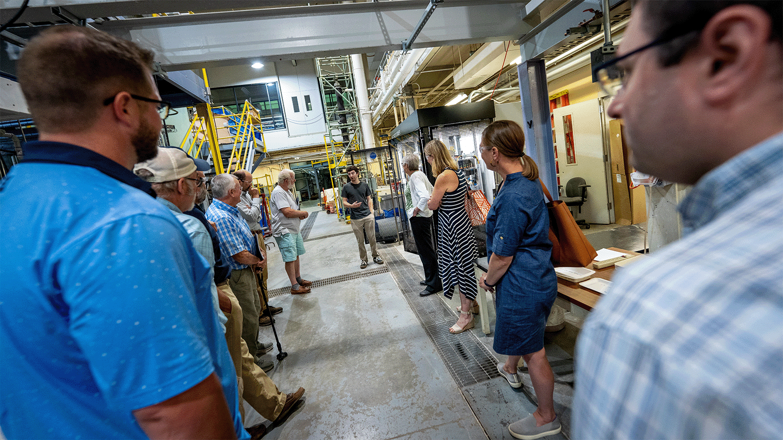 People stand and observe a piece of machinery during a tour of the Process Development Center.