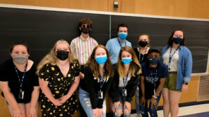 Eight Upward Bound students stand together in their group before a chalkboard