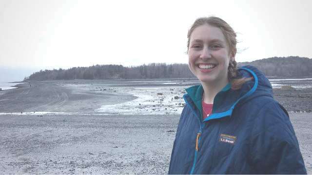 Photo of Caitlin McGuire standing in front of waves.