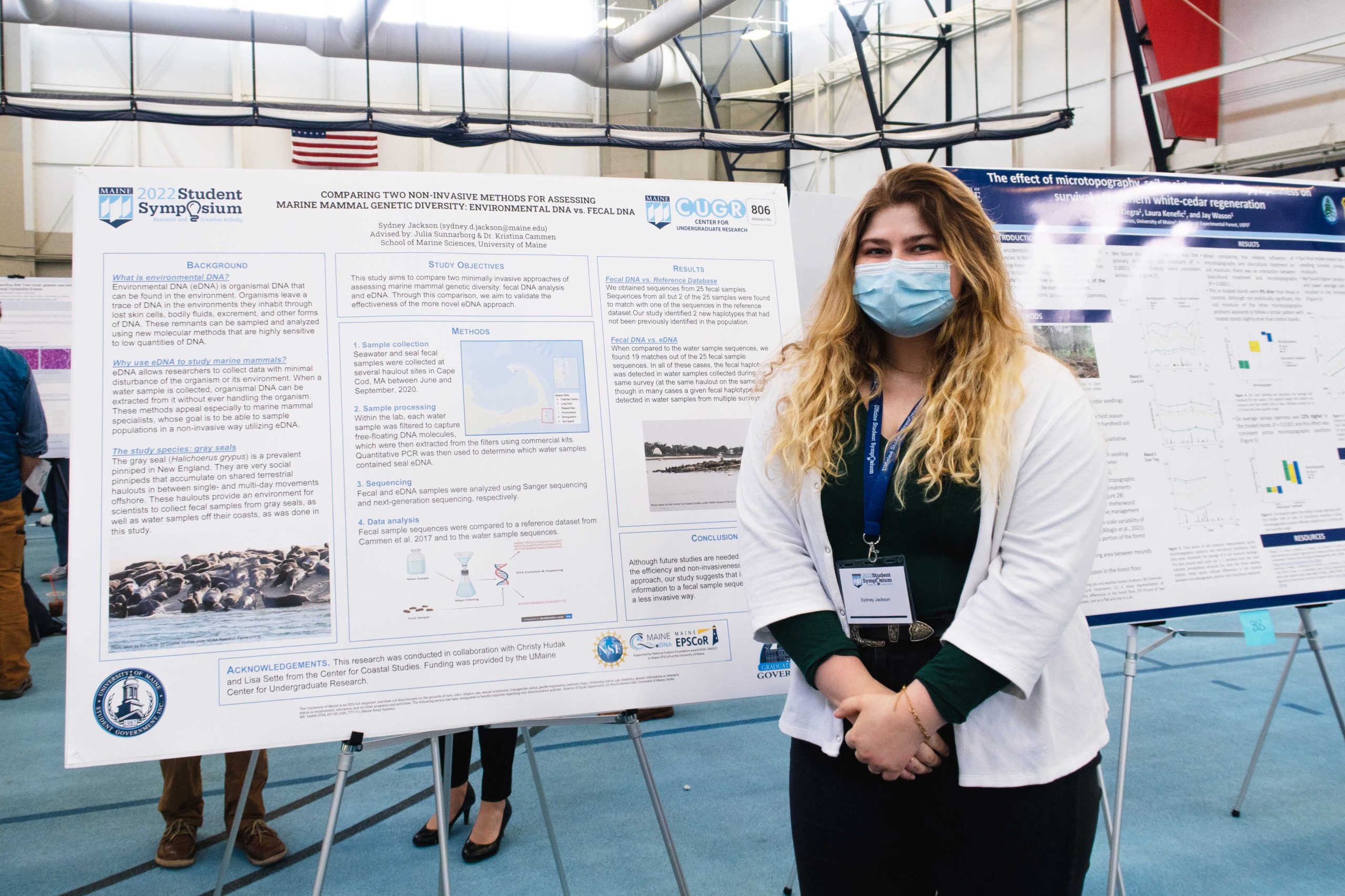 Sydney Jackson stands to the right of her poster wearing a white jacket.