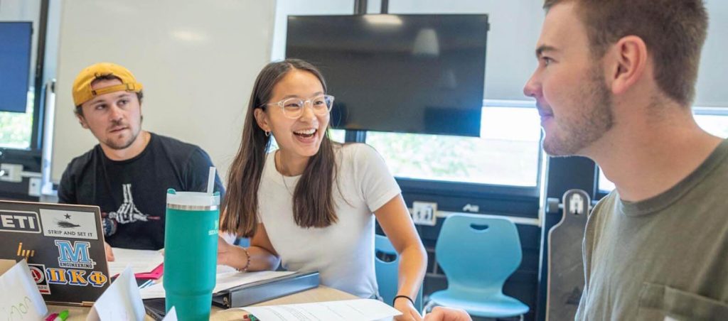 A photo of three students working together in a classroom