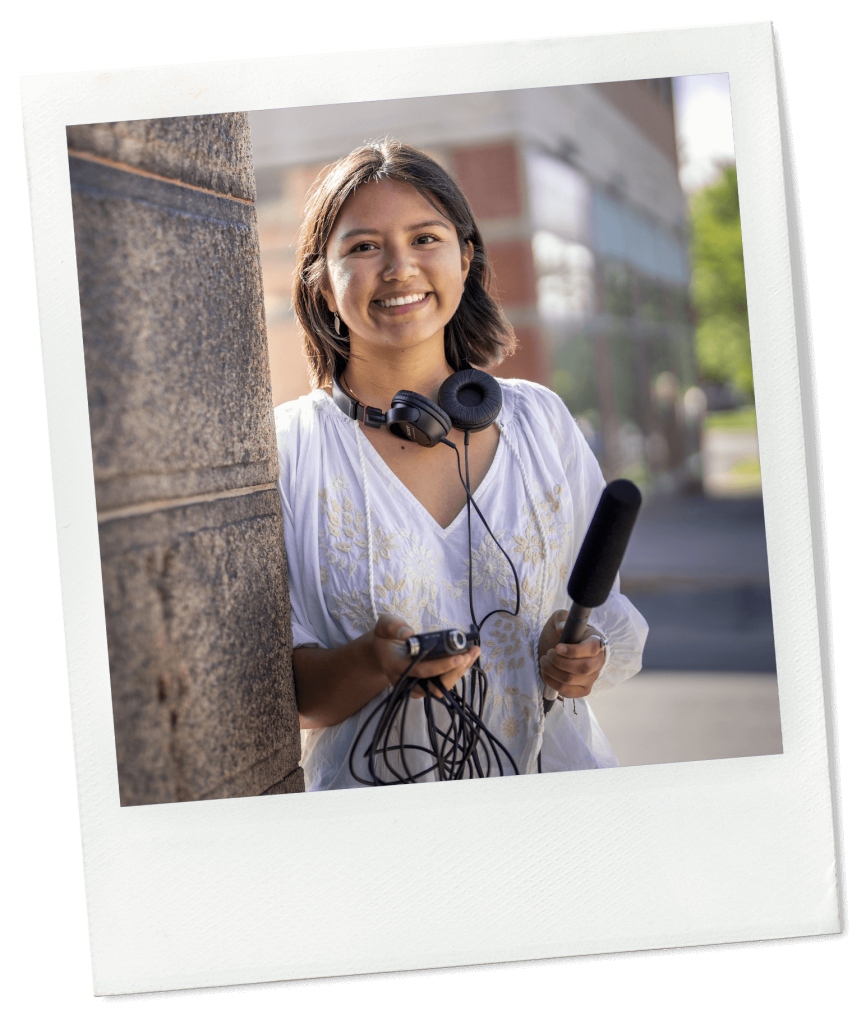 A photo of a communications student holding a microphone and recording device