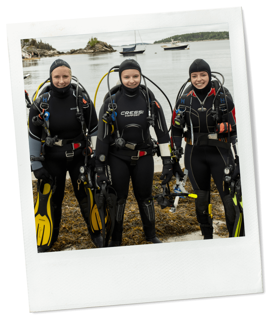 A photo of three students in diving gear on Maine's rocky coast