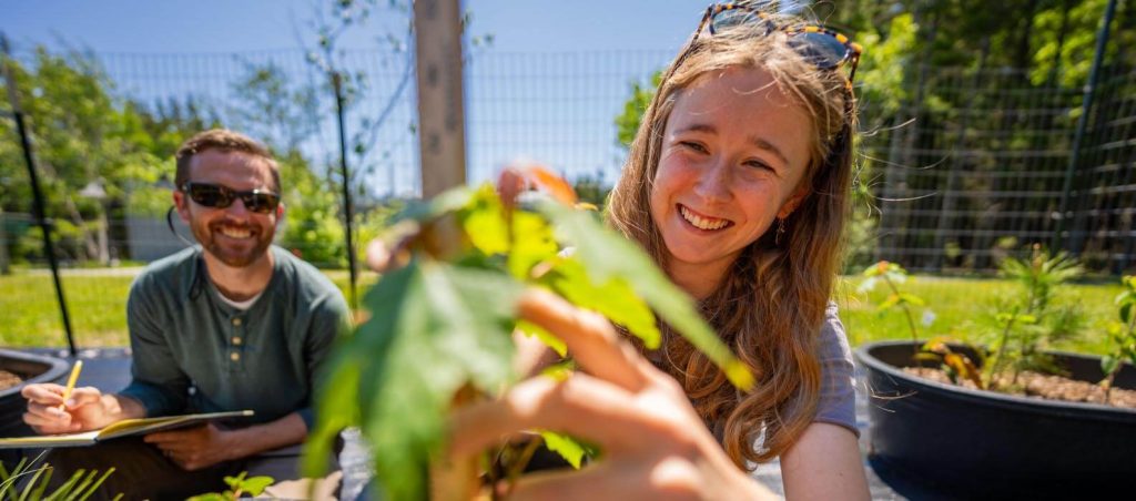 A photo of a student and professor look at plant in an outdoor garden