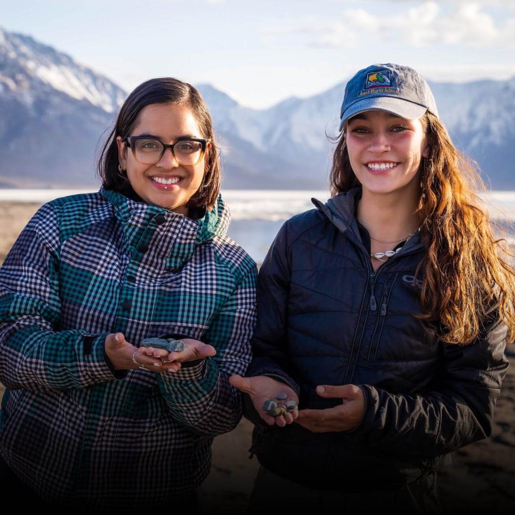 A photo of students holding rocks in front of snowy mountains