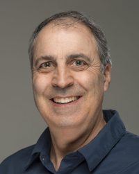Bill DeSisto wearing a dark collared shirt and smiling