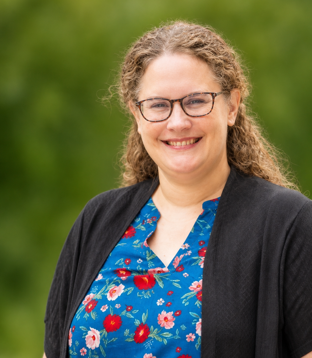 Sara Flanagan Smiling with a patterned shirt and blazer.