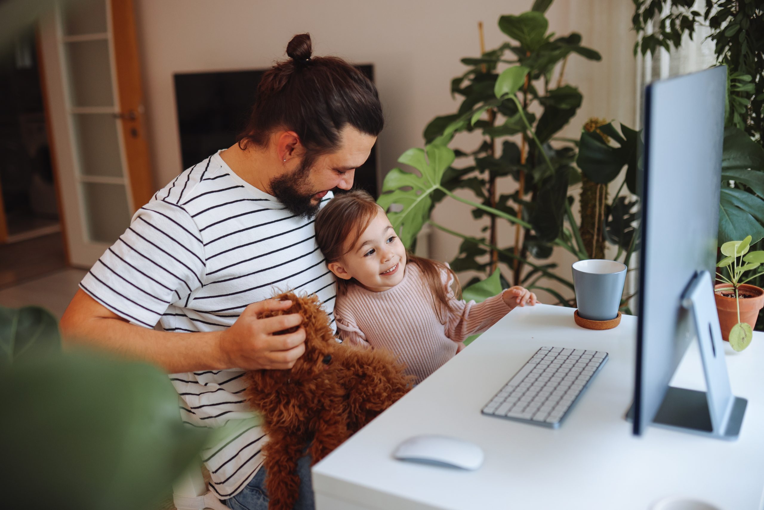 Adult student working on a computer with a child and dog
