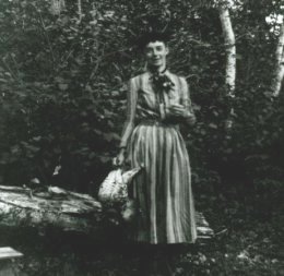 P00342 Fannie P. Hardy (Eckstorm) standing in the woods holding one or more dead grouse.