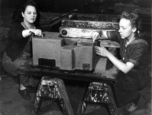Ethel Linscott and an unidentified co-worker, working in the core room at the Saco-Lowell Foundry in Biddeford, Maine sometime in 1942 or 1943. "I worked in what they called the core room. You can imagine the jokes that come from that! Talk about pounding sand, that's where you pound sand! The sand was mixed with oil, and you had molds, and you pounded this sand into the molds. Then you had to take the sides off the molds very carefully to get the things to come apart without falling apart. My hands weren't as delicate as they should be, and this was quite a job." [P 5252] [NA 1532.007]