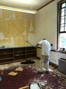 Facilities worker priming walls of former archive room.