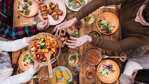 Top view of four people having dinner together while sitting at the rustic wooden table