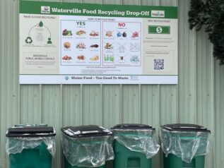 Image of the Waterville transfer station: features four recycling bins under a food recycling sign