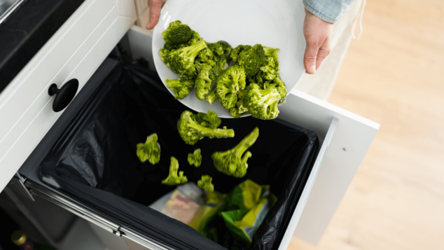 picture of a person dumping broccoli into the trash