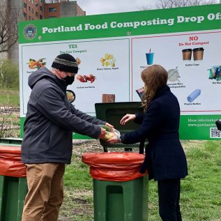 Image of two people demonstrating how to dispose of food waste at Portland city launch