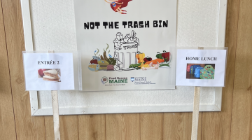Poster designed by student intern, Eddie Nachamie, in Sebago Elementary School cafeteria near food waste sorting stations. Poster reads, "Feed your Body! Not the Trach"