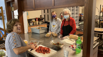 Three women smiling in a kitchen.