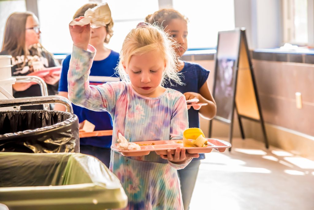 student participates in sorting her food waste at Lisbon Community School.