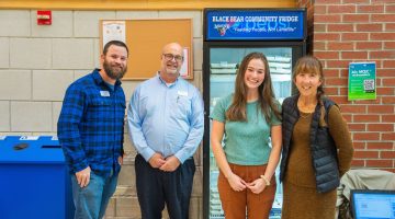 Four people standing in front of UMaine's Community Fridge