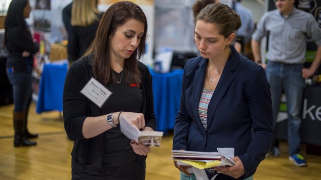 Two woman looking over a career fair brochure.