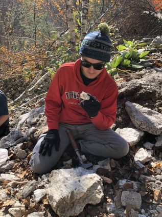 Thomas sitting on the group looking at a sample he just broke off