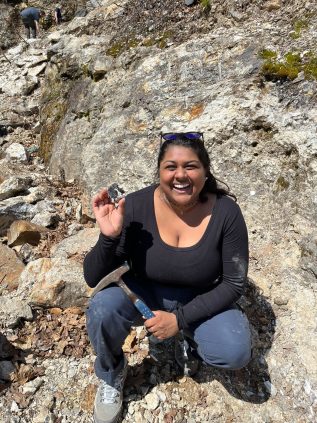 Kavya holding a rock hammer and a cool sample she collected