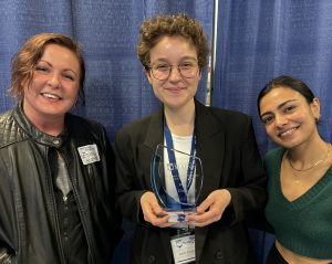 Leah Cingranelli holding the Dr. Susan J. Hunter Presidential Research Impact Award, alongside Dr. Patricia Goodhines (left) and Krutika Rathod (left)